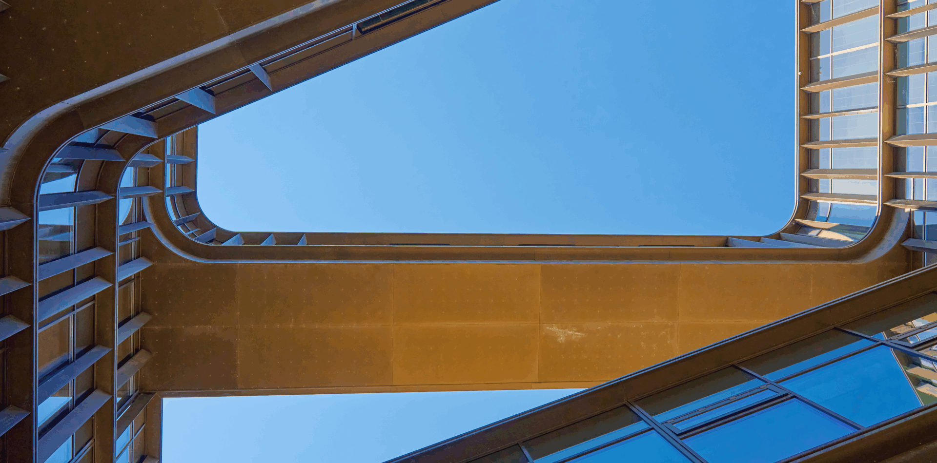 Yellow pedestrian bridge between buildings under a clear blue sky.
