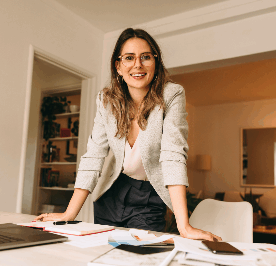 Confident woman leaning on a table with documents in a cozy office.