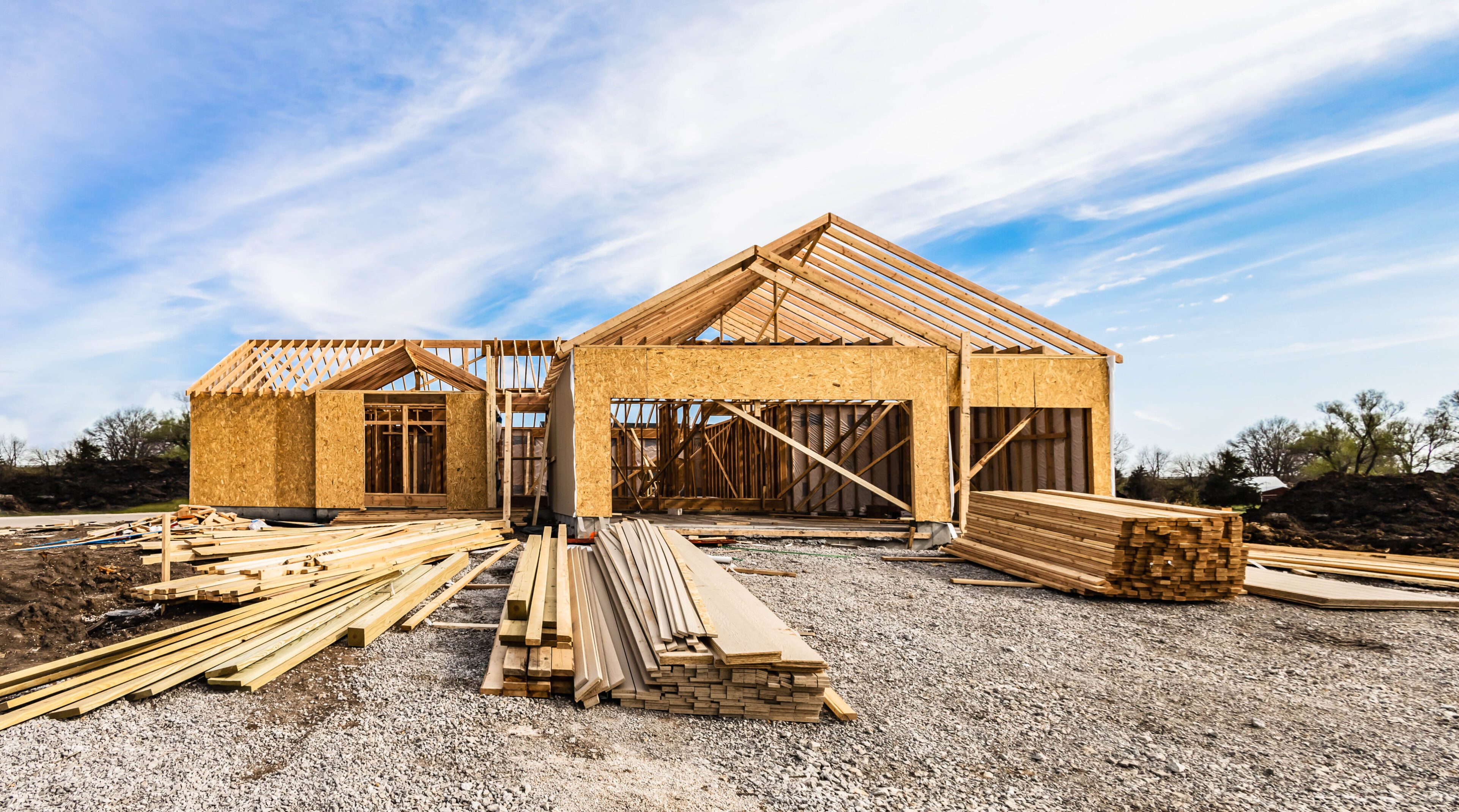 Wooden house frame under construction on a clear day.