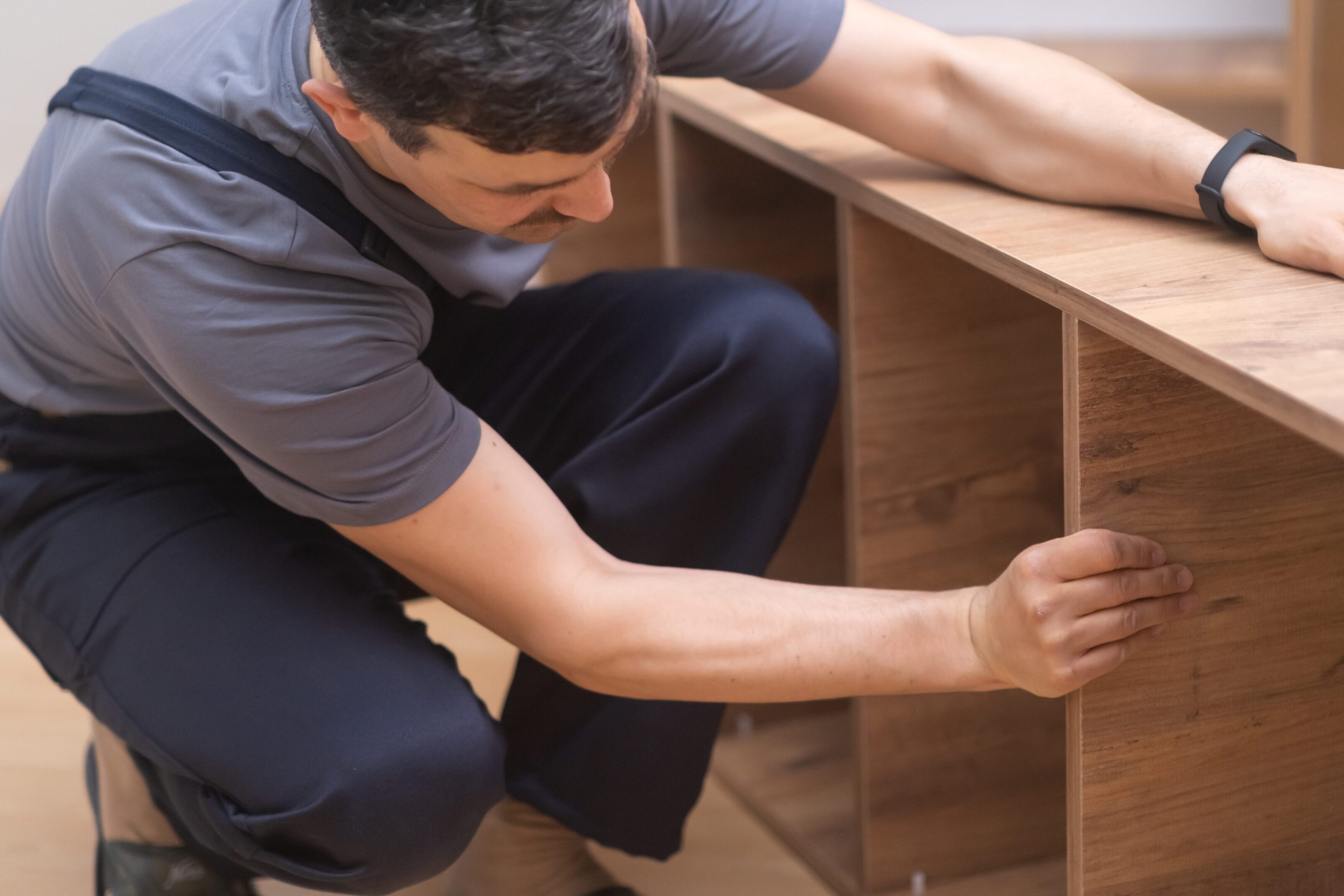 Man assembling wooden furniture with tools.