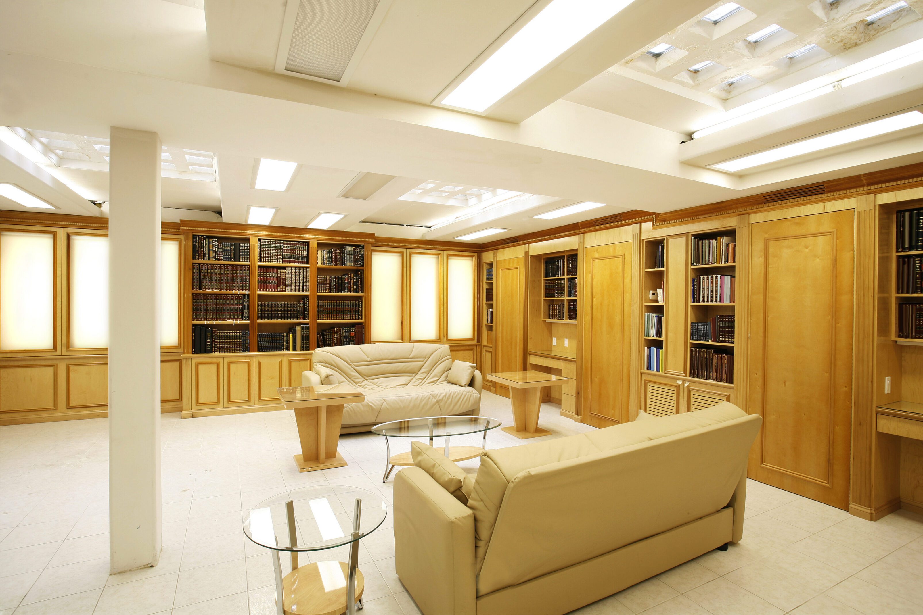 Elegant home library with wooden shelves and cream sofas.