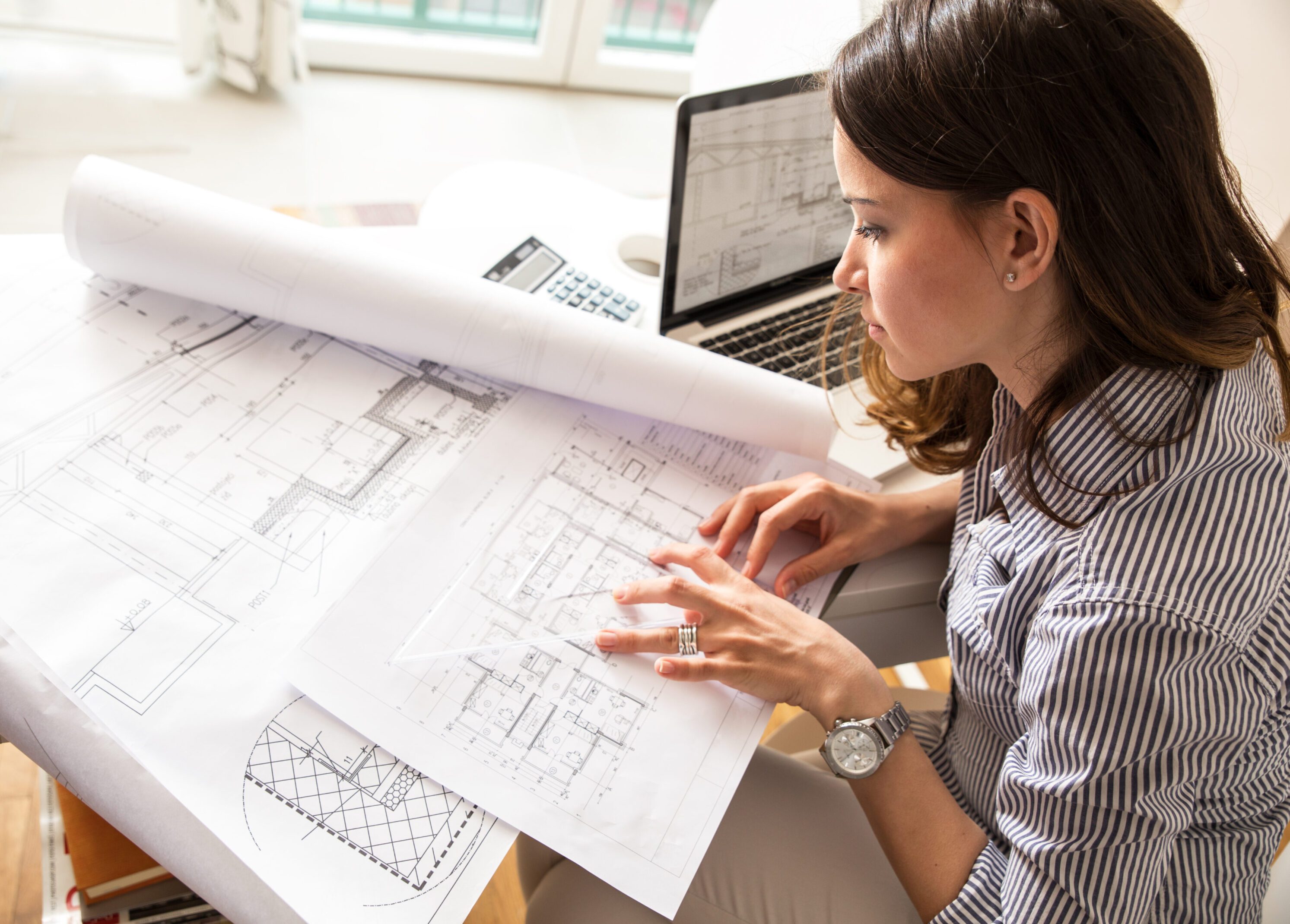 Woman reviewing architectural blueprints at her desk.