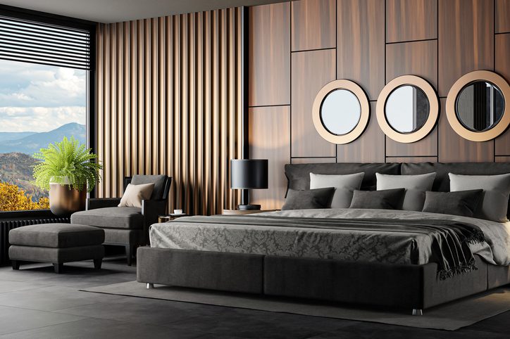 Modern bedroom with a stylish bed and round mirrors on wooden panel walls.