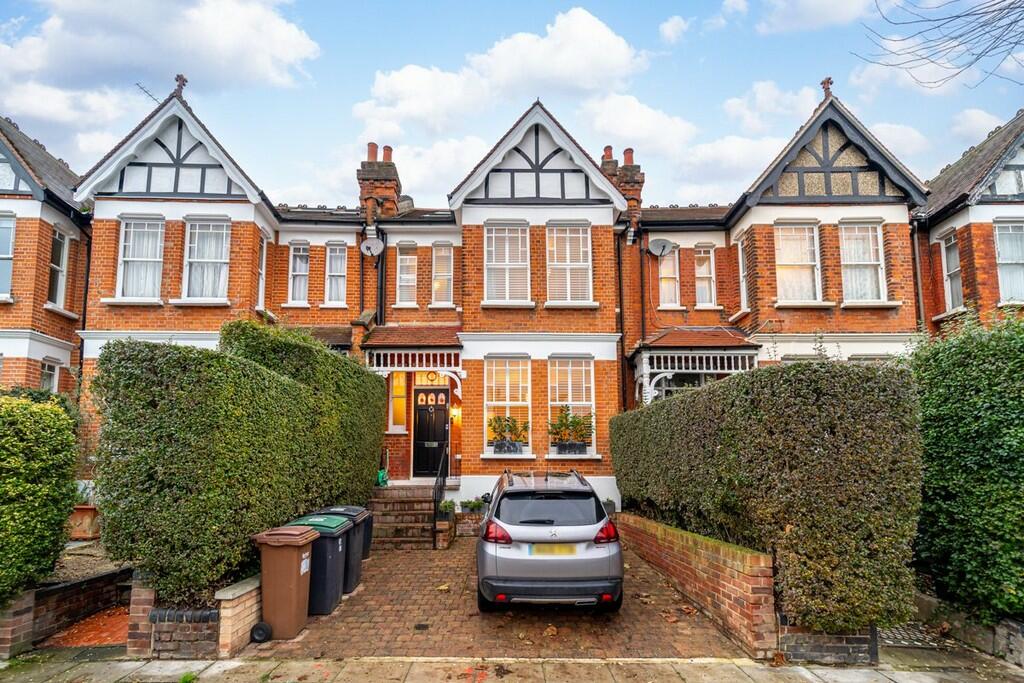A classic brick townhouse with a driveway and neatly trimmed hedges.