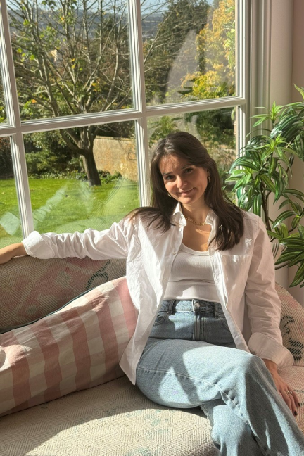 Young woman relaxing by a window with greenery outside.