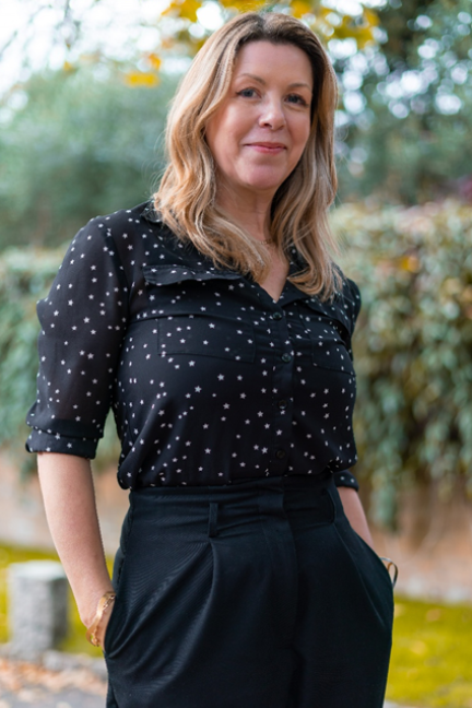 Woman in a black blouse with white polka dots and black pants.
